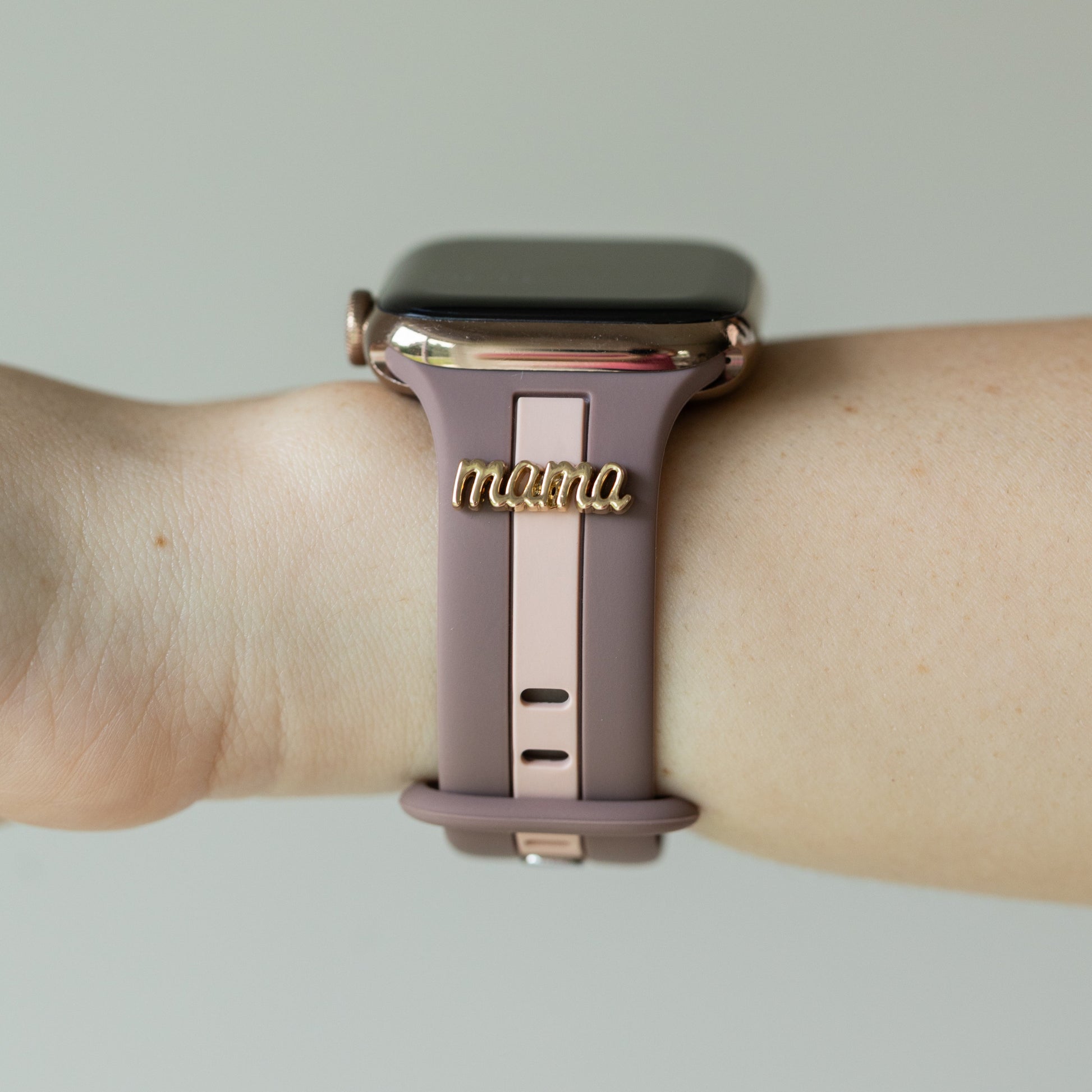 Smartwatch with a 'mama' band on a wrist against a neutral background
