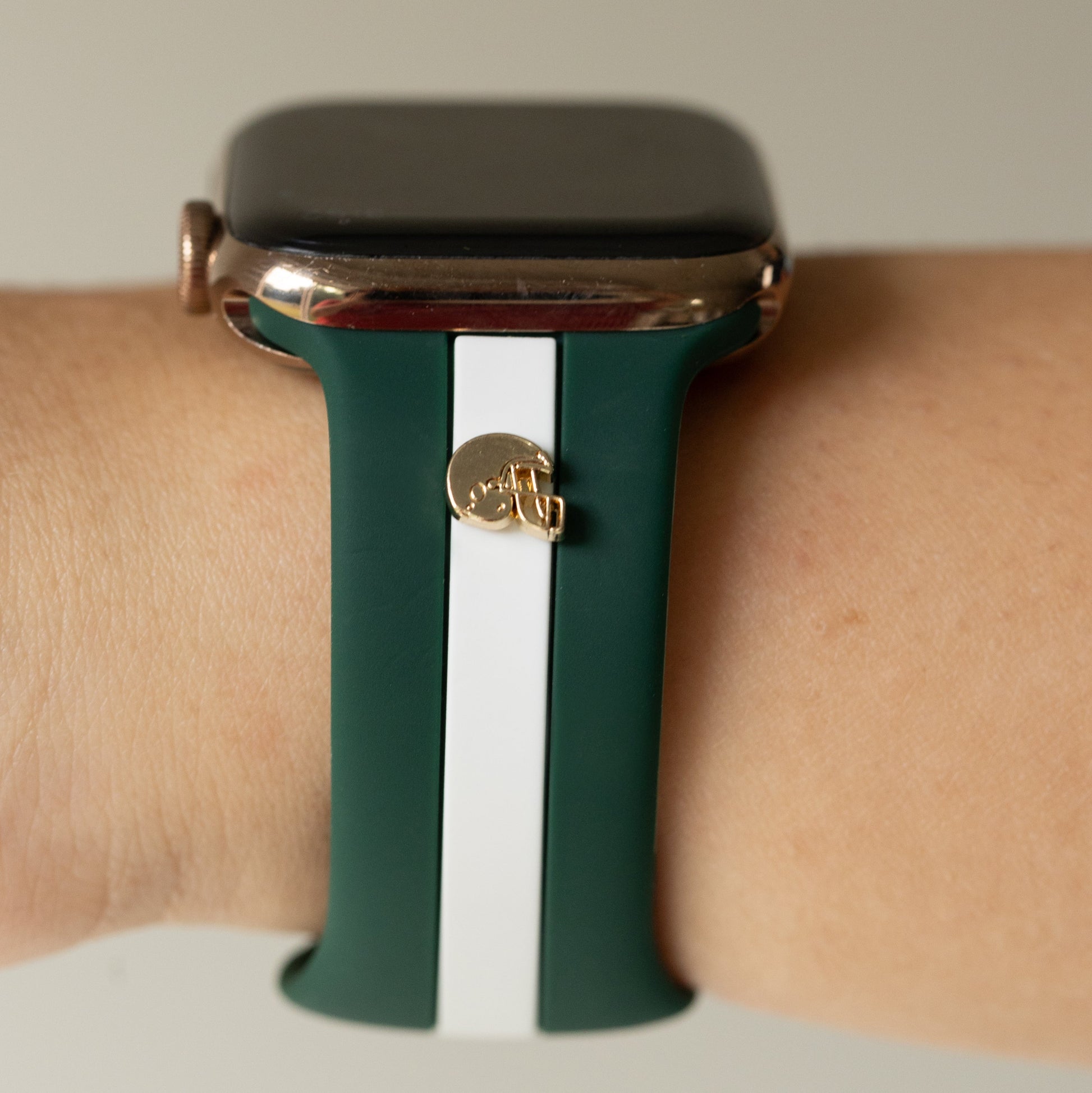 Smartwatch with a green and white striped band on a wrist against a neutral background