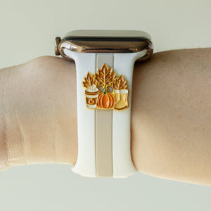 Smartwatch with a decorative band featuring pumpkins and leaves on a wrist against a neutral background