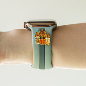 Smartwatch with a decorative band featuring pumpkins and leaves on a wrist against a neutral background